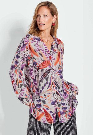 Blouse à manches longues ornée d'un motif floral et de feuilles vibrant en violet, rouge et orange sur un fond clair. Design à boutons à l'avant, ourlet arrondi.
