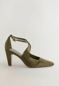 Olijfgroene satijnen hoge hak schoen, spitse neus, enkelbandje met verstelbare gespsluiting en een gestructureerde beige zool.