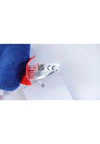 Blue plush fabric with a soft texture, featuring a red tag with CE certification and care information attached to a white card.