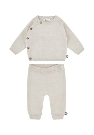 Knitted beige sweater with side buttons and a textured pattern, paired with matching beige pants featuring a ribbed waistband.