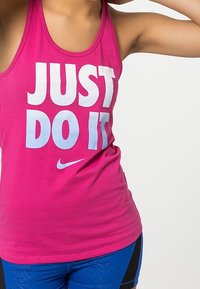 Top da donna Nike rosa con testo bianco e azzurro chiaro "JUST DO IT" e logo. Il materiale è liscia, senza maniche, aderente al corpo.