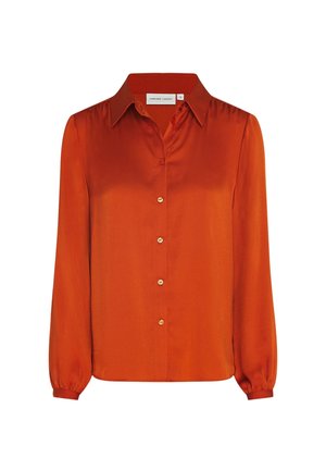 Blouse en soie orange à manches longues, col pointu, boutonnage sur le devant et poignets froncés sur fond blanc.
