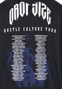Schwarzer Hoodie mit dem Text "DROP SIZE HUSTLE CULTURE TOUR" in Weiß, mit einer Liste von Städten auf der Rückseite, akzentuiert durch blaue Flammen.