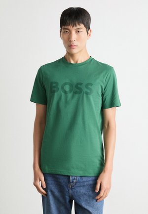 Grünes Baumwoll-T-Shirt mit rundem Ausschnitt und kurzen Ärmeln, das ein großes, dunkelgrünes "BOSS"-Logo auf der Brust aufweist.