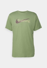 Camiseta de algodón verde con mangas cortas, que presenta la palabra "Training" en beige y un logo de swoosh de Nike en marrón oscuro.