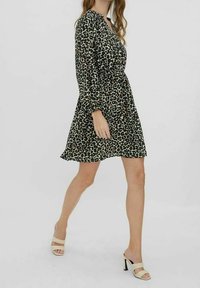 Naritettu leopardikuosiset mekko kevyestä kankaasta, jossa on korostettu vyötärö, pitkät hihat ja levenevä helma. Mallilla on päällään korolliset sandaalit.