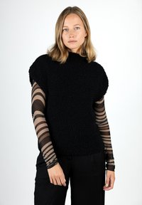 Black textured knit sweater with a high neckline and short sleeves, layered over a sheer striped long-sleeve top. Worn with black pants.