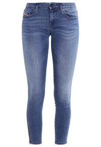 Jeans de mezclilla azul skinny con un ligero desvanecimiento, diseño de cinco bolsillos, cierre de botón metálico y cremalleras en los dobladillos para ajustar el ancho.
