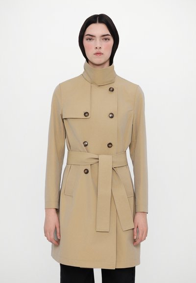 Beige trench coat with high collar, double-breasted design, button accents, tied waist, and side pockets. Smooth fabric, tailored fit.