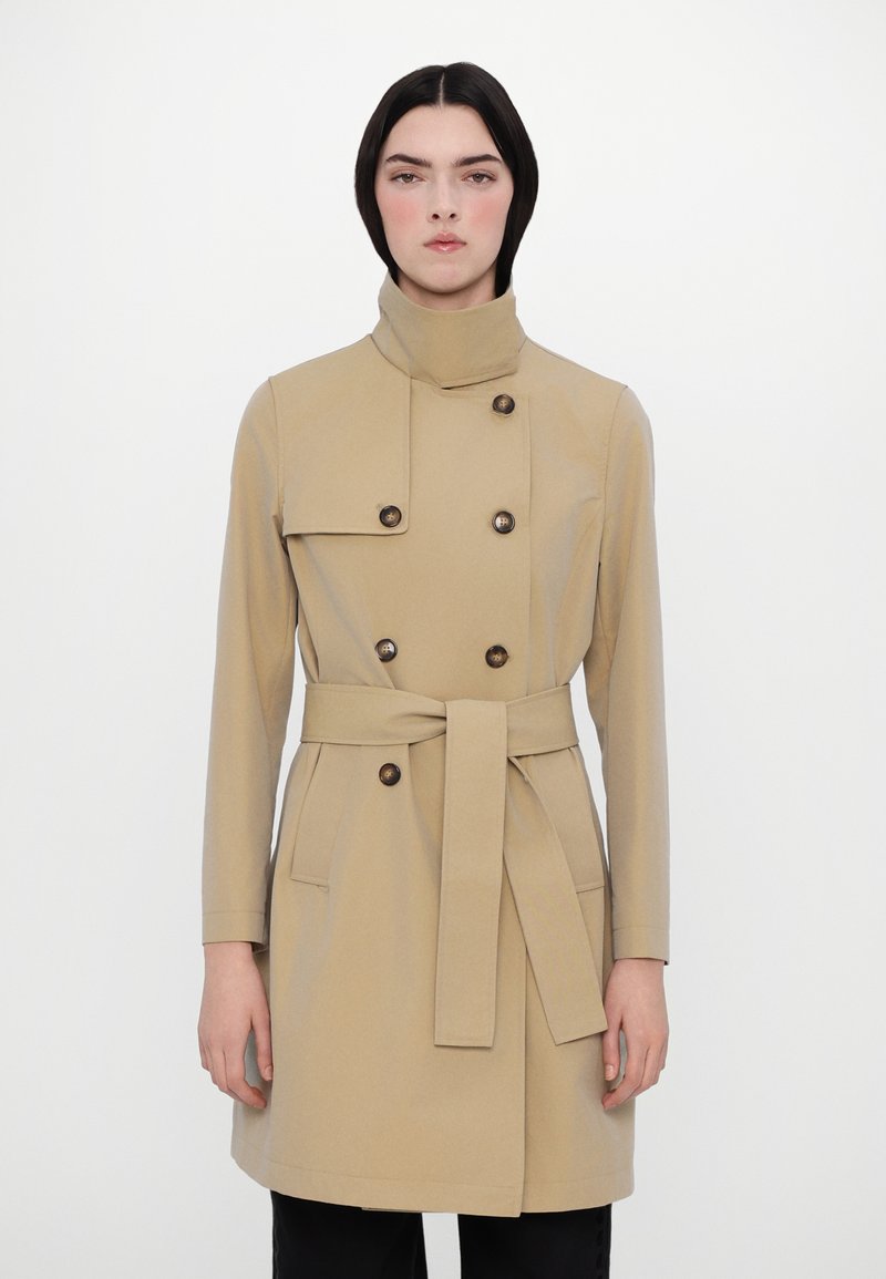 Trench coat bej cu guler înalt, design cu două rânduri de nasturi, accente cu nasturi, talie legată și buzunare laterale. Material neted, croială ajustată.