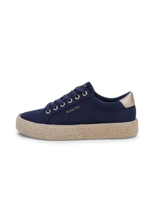 Sneaker blu navy basso con suola piatta intrecciata beige, linguetta beige sul tallone, lacci rotondi e logo "Armor-lux" dorato sul lato.