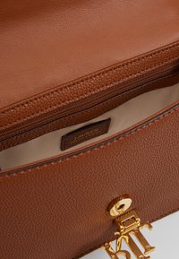 Brązowa torebka skórzana o fakturowanej powierzchni z złotymi akcentami. Wewnątrz znajduje się kieszeń na zamek oraz metka z wytłoczonym napisem.