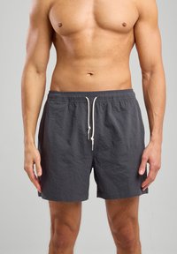 Harmaat uimapuvut, joissa on teksturoitu kangas, joustava vyötärö ja säädettävä nyöri. Sortseissa on sivutaskut ja ne ulottuvat reiden keskivaiheille.