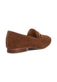 Brown suede loafers with a flat heel, featuring a small decorative gold hardware accent on the upper. Smooth texture and simple design.