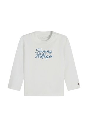 Wit overhemd met lange mouwen met "Tommy Hilfiger" in blauwe letters op de voorkant en een klein Tommy Hilfiger-logo op de linker mouwmanchet.
