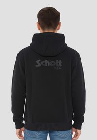 Schwarzer Kapuzenpullover mit einer vorderen Kängurutasche und gerippten Bündchen. Auf der Rückseite befindet sich ein großes "Schott N.Y.C."-Logo. Aus einer Baumwollmischung gefertigt.