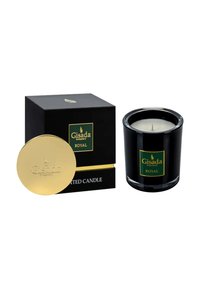 Bougie en verre noir avec couvercle doré, ornée d'une étiquette verte et dorée, conditionnée dans une boîte noire assortie. Accents texturés sur le couvercle.