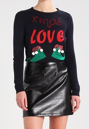 Granatowy sweter z czerwonym napisem "Xmas LOVE" i ozdobami w kształcie elfich bucików, zestawiony z czarną błyszczącą skórzaną mini spódniczką.