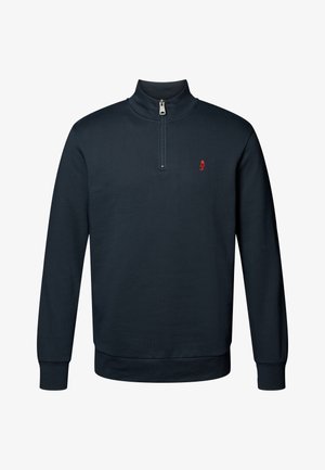 Námořnická modrá mikina s vysokým límcem a čtvrtinovým zipem, s malou červenou nášivkou na hrudi a ribbenými manžetami a lemem.