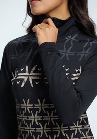 Langsleeve, aangesloten top van zwarte stof. Heeft een hoge kraag en decoratieve geometrische patronen in donkergrijs en beige. Subtiele logo-detail.