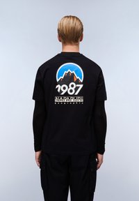 Sort bomuld t-shirt med et farverigt bjergmotiv, en blå himmel og teksten "1987", samt "Napapijri geographic" brandet nedenfor.