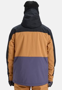 Skijacke mit einem mehrfarbigen Design aus schwarzen, orangefarbenen und lila Paneelen. Hergestellt aus einem strukturierten, wasserdichten Material und verfügt über eine Kapuze.