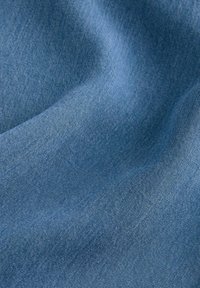 Denim-kangas keskiharmaassa sävyssä, jossa on sileä rakenne, hieman värivaihteluita ja hienovaraisia kudontakuvioita.