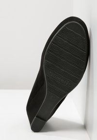 Black suede shoe sole with textured grooves, flat design, and embossed brand name "Tamaris." Size 35 indicated near heel.