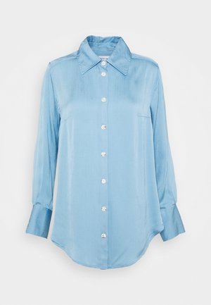 Lyseblå skjorte i let materiale med glat tekstur, der har spids krave, lange ærmer og en venstre brystlomme.
