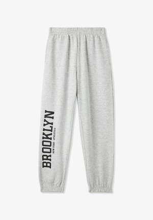 Pantaloni grigi in felpa con vita elastica. Presentano la scritta stampata nera "BROOKLYN NEW YORK ATHLETICS" lungo la gamba sinistra. Vestibilità standard a gamba affusolata.
