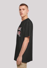 Black cotton t-shirt featuring bold, multicolored text reading "LOVE" and "WAR." Short sleeves, relaxed fit, visible stitching at the neck.