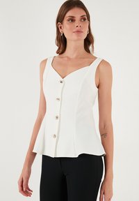 Fehér peplum topp V-nyakkivágással, elöl négy arany tónusú gombbal és széles vállpántokkal. Simával felületi textúra.