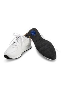 White athletic shoes with textured leather upper, padded collar, and black rubber sole featuring a blue accent on the heel.