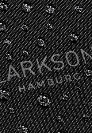 Gouttes d'eau éparpillées sur un tissu sombre et texturé avec un texte partiellement visible "LARKSON HAMBURG."