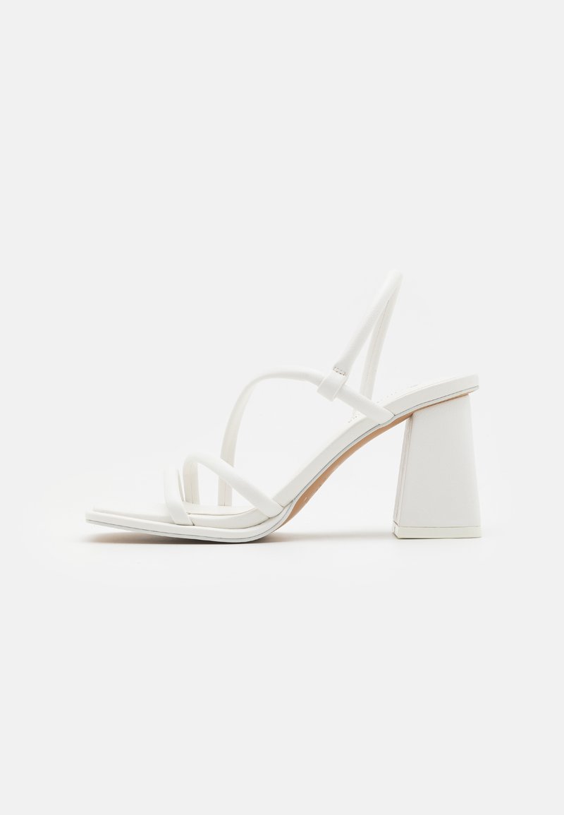 Sandales à talons blancs avec des brides fines, un bout carré et un talon bloc épais, au texte lisse et au design minimalist.