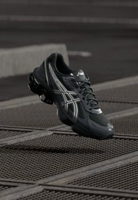 Melnas sporta kurpes ar teksturētu sietu augšdaļu, atstarojošiem akcentiem un amortizētu zoli. Gluds, viegls dizains ar auklām.