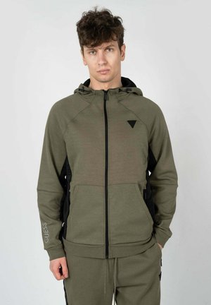 Olive green zip-up hoodie made of soft material, featuring black side panels, a hood, and a small logo on the left chest.