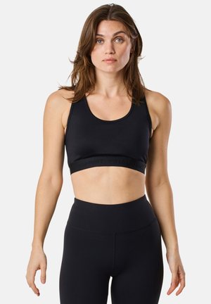 Black sports bra with a rounded neckline and wide straps, featuring a textured underband. Paired with black high-waisted leggings.