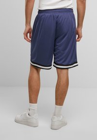 Shorts de sport bleu marine avec une coupe décontractée, ornés de accents rayés noir et blanc en bas et d'une taille élastique.
