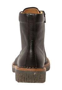 Bota negra de cuero hasta el tobillo con una superficie lisa, costuras decorativas y un tacón elevado. Presenta un cierre con cremallera y una suela texturizada.