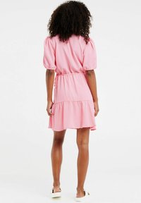 Vestito rosa a maniche corte con orlo volants, vita definita e tessuto testurizzato. Presenta maniche a palloncino e silhouette rilassata.