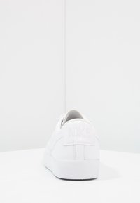 Zapatilla Nike blanca con cuero suave y una suela de goma texturizada. Presenta un logotipo sutilmente embossado en el talón y un diseño clásico de cordones.