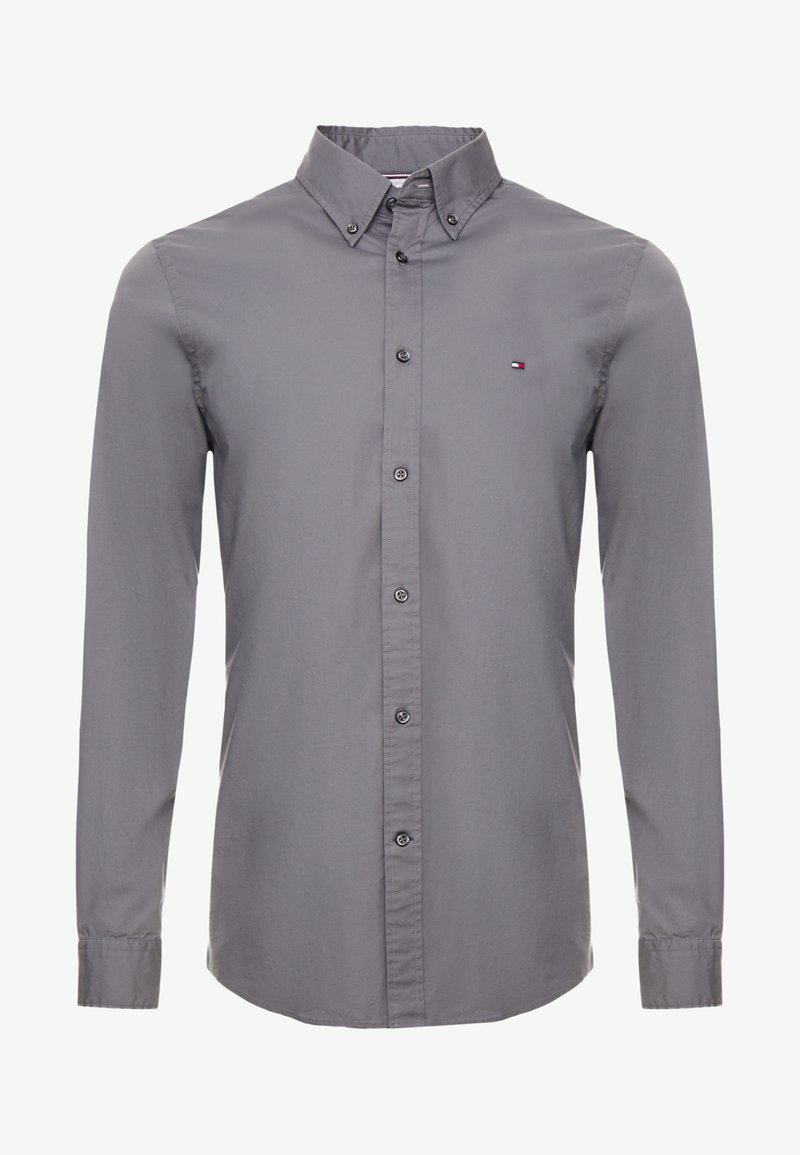 Chemise à manches longues pour homme en gris, en coton. Possède un col avec boutons, une fermeture par boutons à l'avant et un petit logo brodé sur la poitrine.