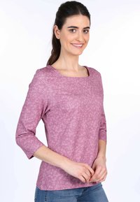 Helllila Bluse mit quadratischem Ausschnitt und dreiviertel Ärmeln, mit floralem Muster, aus einem weichen, glatten Stoff.