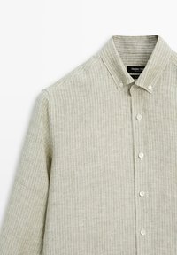 Light beige long-sleeve button-up shirt with fine vertical white stripes and buttoned collar shown from the front and left side.