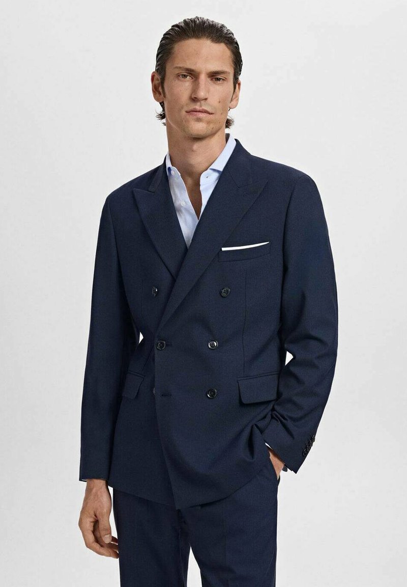 Double-breasted navy suit jacket with black buttons, notched lapels, and a white pocket square. Smooth texture, tailored fit.