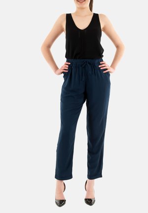 Top senza maniche nero e pantaloni con cordino blu navy, tessuto liscio, vestibilità comoda, abbinati a tacchi alti neri, dettagli di design minimali.