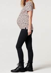 Pink short-sleeve top with black speckled pattern, worn with fitted black jeans and lace-up black boots. The top is slightly gathered at the sides.