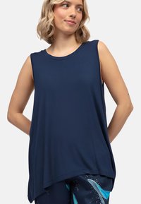 Marineblauwe mouwloze top van zachte stof, met een ronde halslijn, een relaxte pasvorm en een langere achterzoom. Glad van textuur, zonder versieringen.