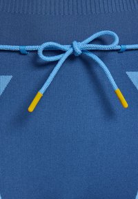 Blauwe stof met een ribbeltextuur heeft een lichtblauw trekkoord dat in een strik is gebonden, verfraaid met gele plastic uiteinden.